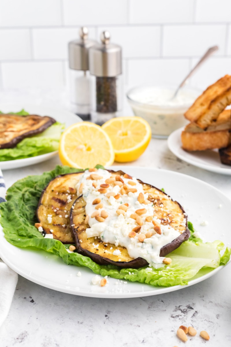 grilled eggplant topped with dressing over lettuce