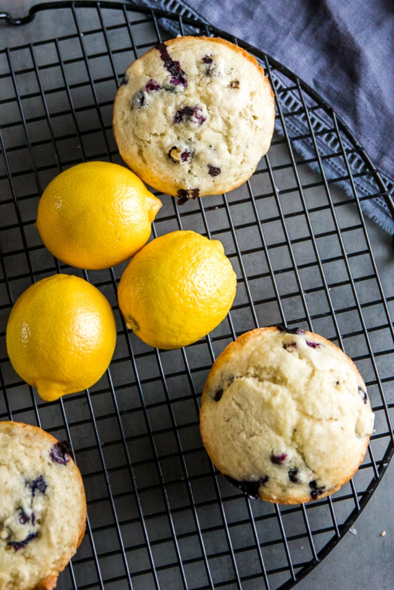 overhead shot of lemon blueberry muffins on a cooling rack with fresh lemons