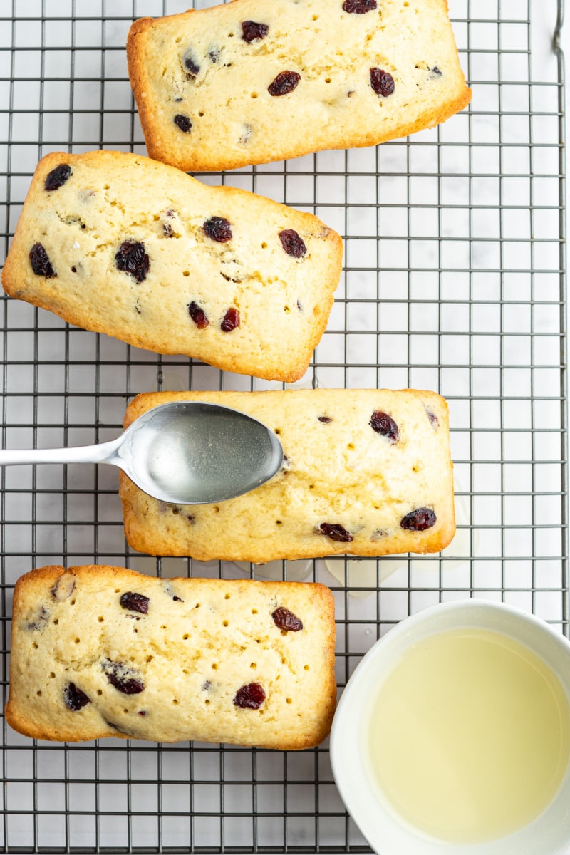 spooning glaze onto cranberry bread