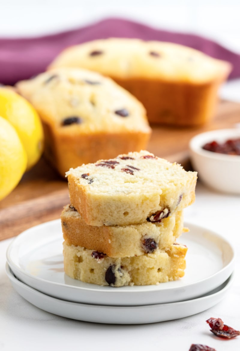 slices of mini cranberry lemon loaf stacked on a plate