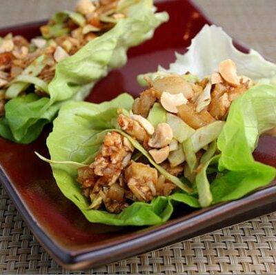 two sweet and spicy lettuce wraps on a burgundy plate