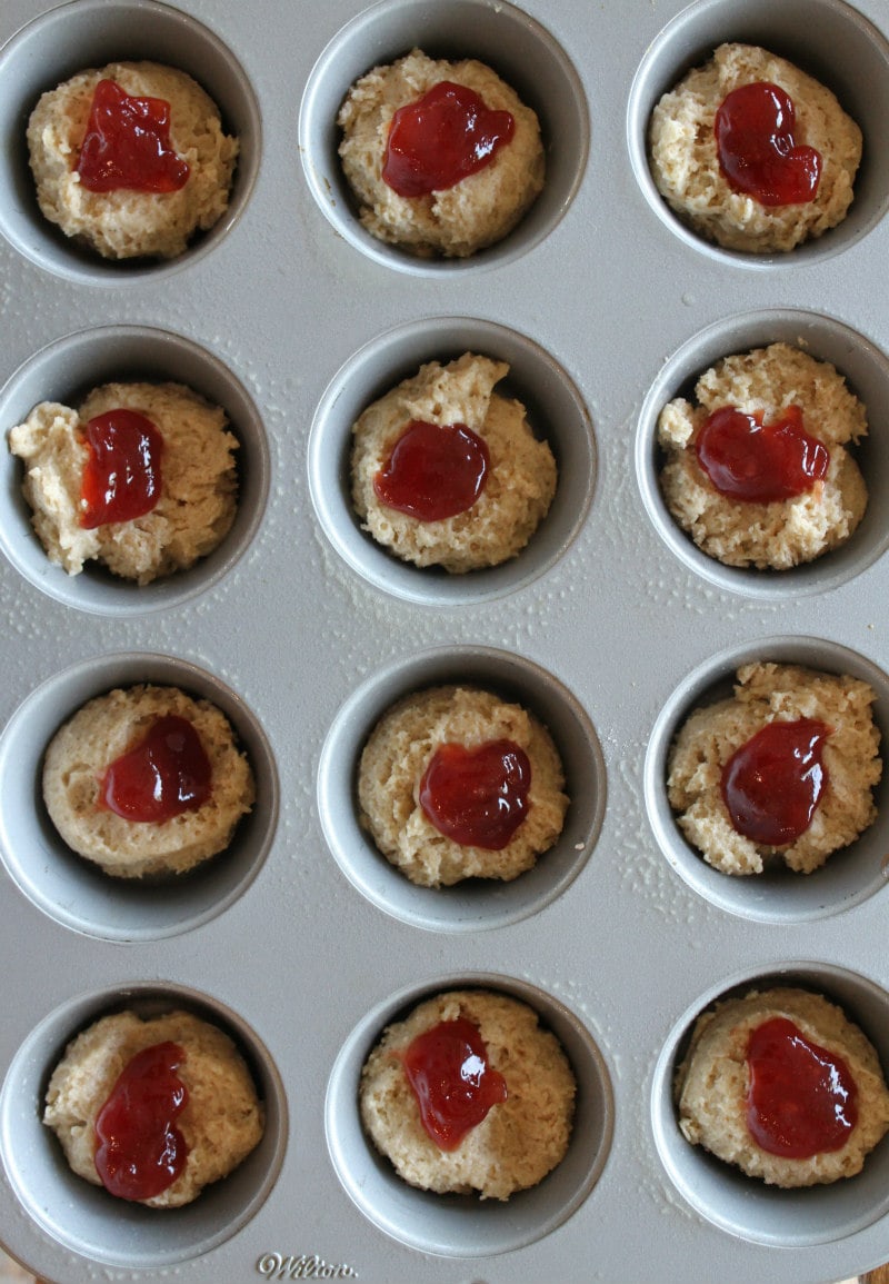 overhead shot of strawberry cinnamon muffin batter with strawberry jam in a muffin tin