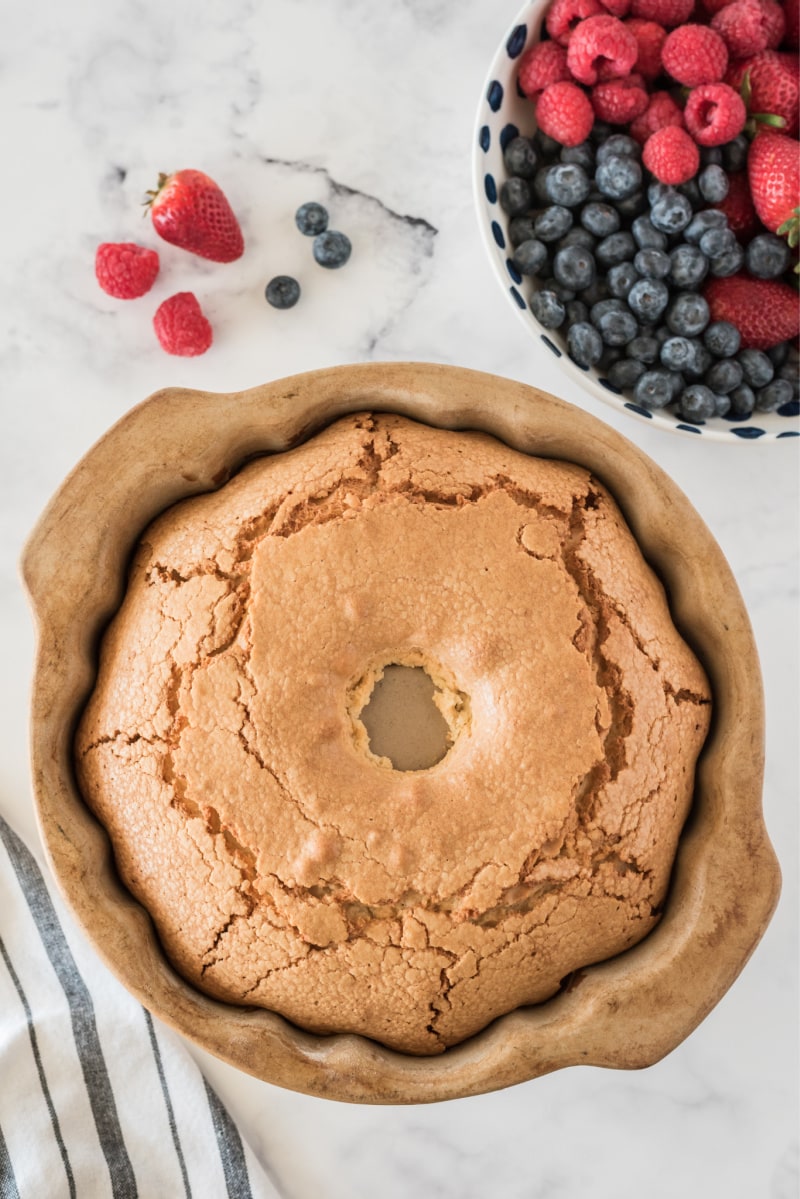 paula deen's cream cheese pound cake in pan just out of oven with berries on the side