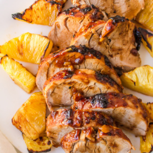 sliced pork tenderloin on a plate with pineapple