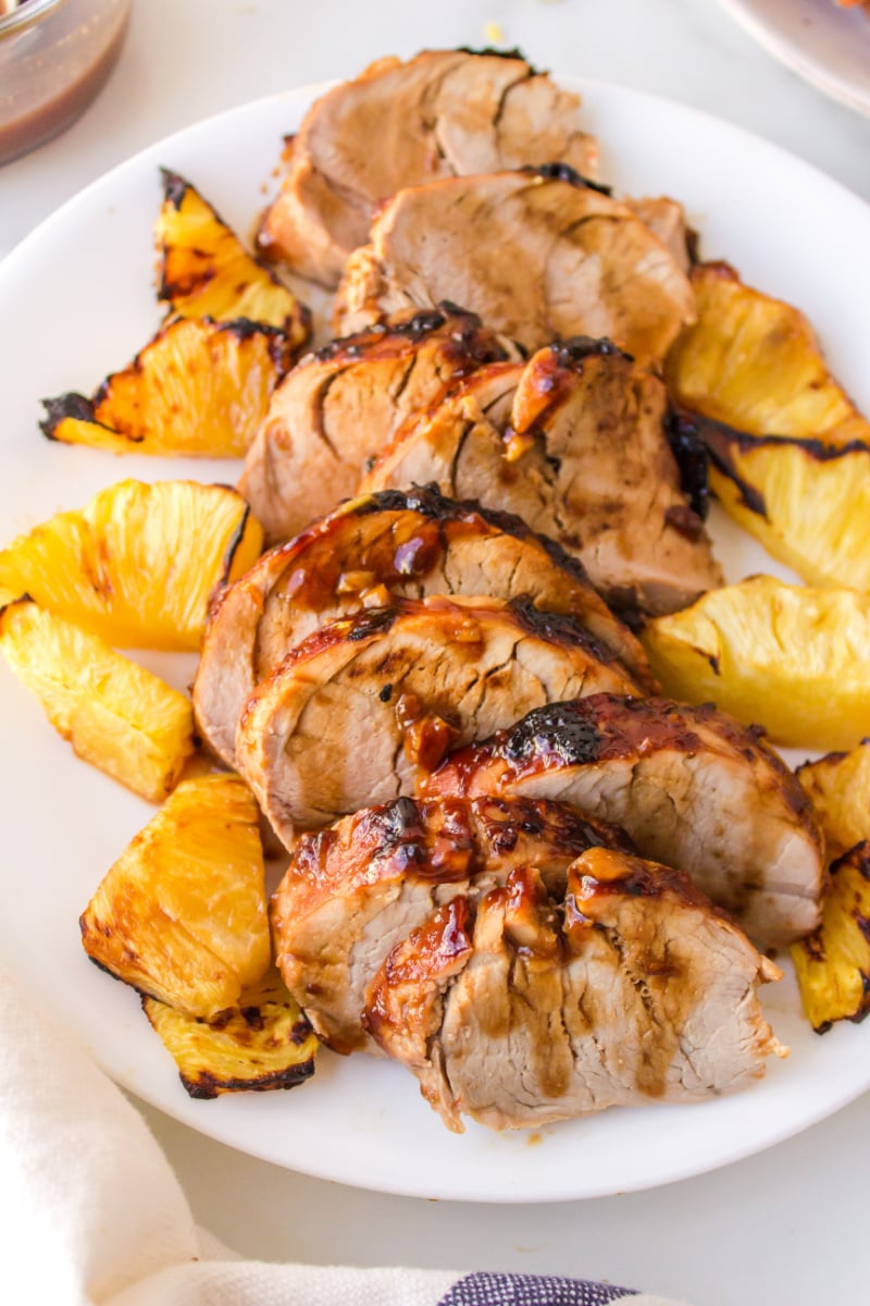sliced pork tenderloin on a plate with pineapple