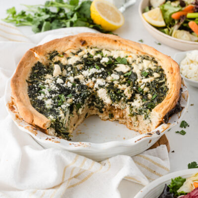 spinach caramelized onion and feta quiche with big slice taken out of it