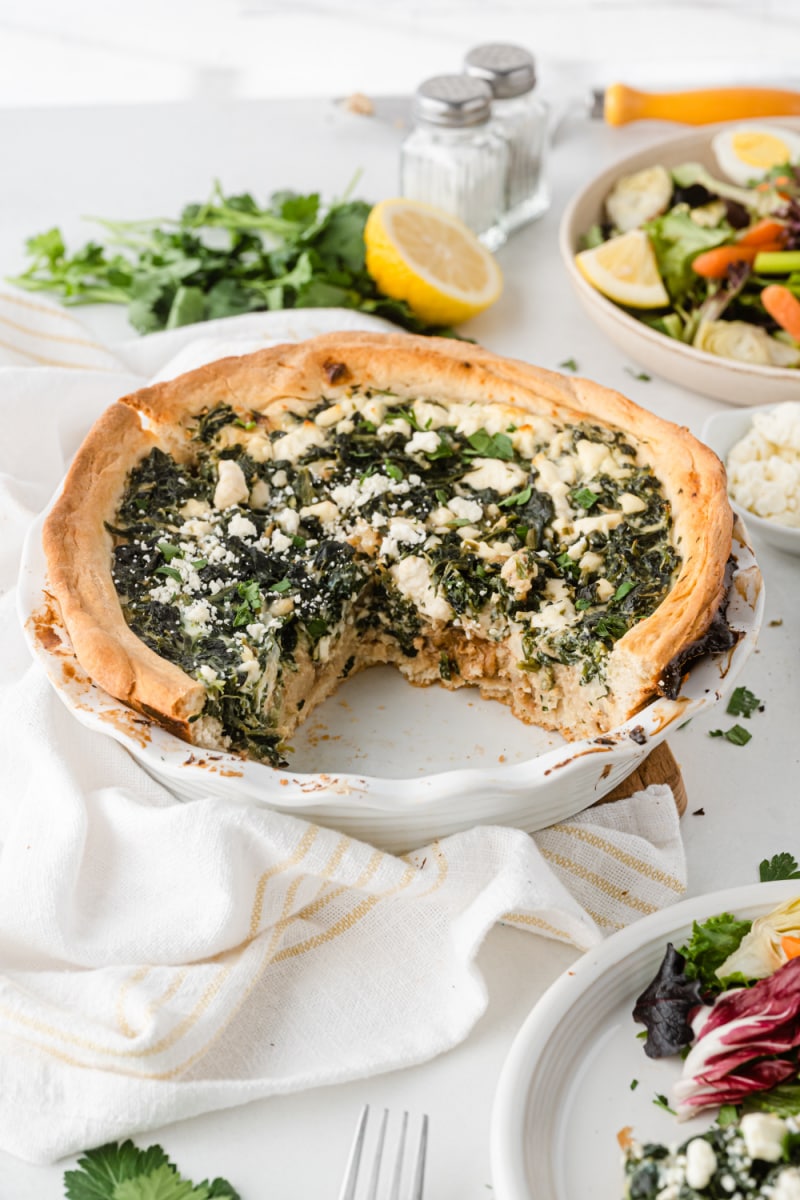 spinach caramelized onion and feta quiche with big slice taken out of it