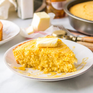 Moist slice of cornbread on plate with butter on top