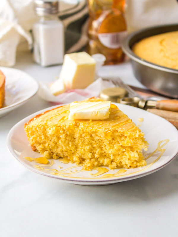 Moist slice of cornbread on plate with butter on top