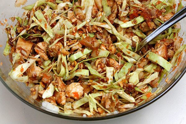 Filling for Sweet and Spicy Chicken Lettuce Wraps in a glass bowl with a spoon