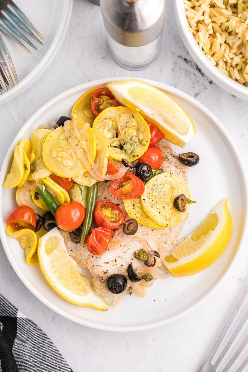 grilled tilapia on a plate with grilled veggies