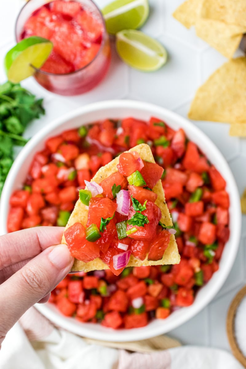 hand holding chip with watermelon salsa
