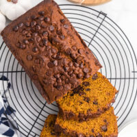 loaf of whole wheat chocolate chip pumpkin bread on a rack sliced open