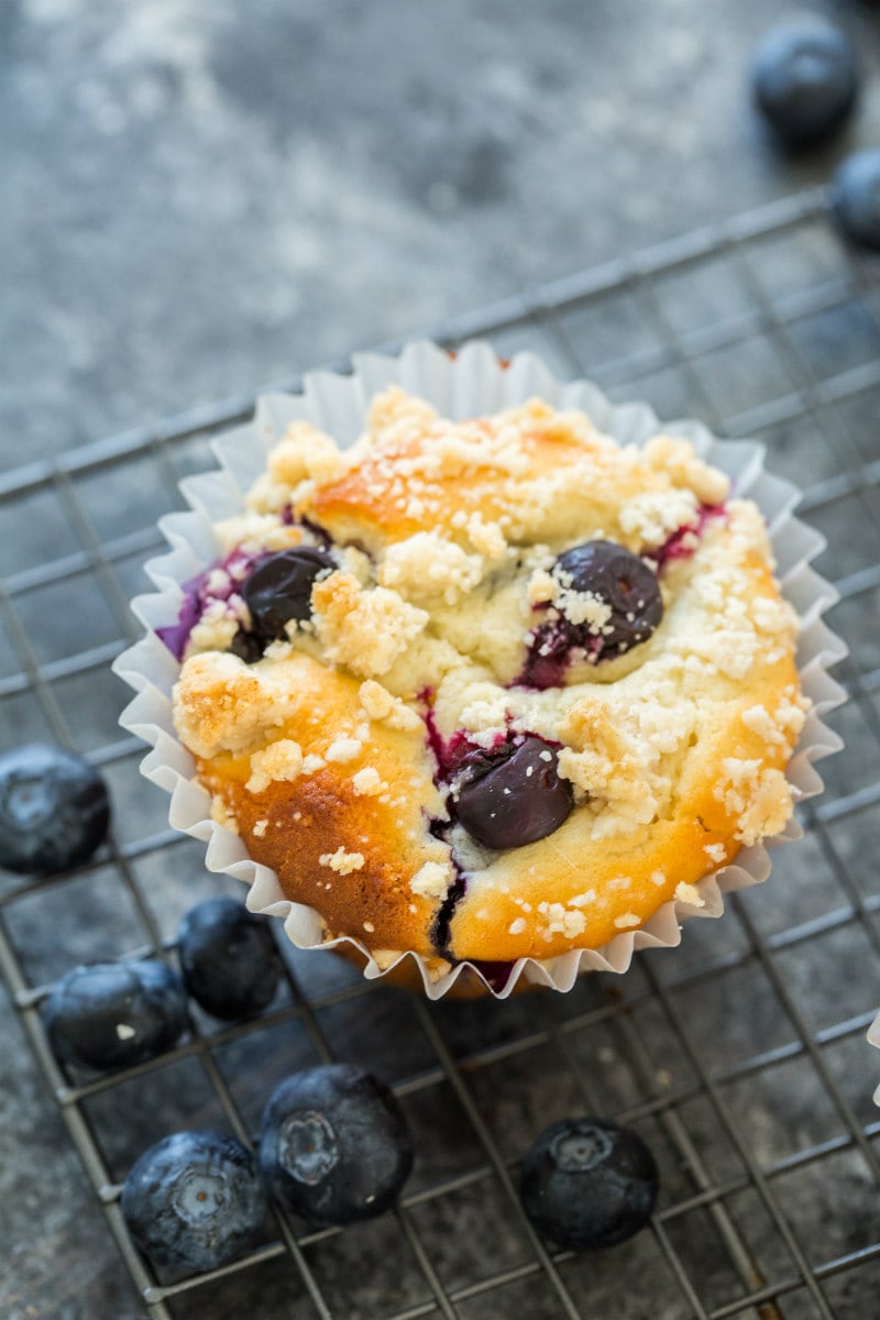 overhead shot of blueberry muffin with a few fresh blueberries in the background