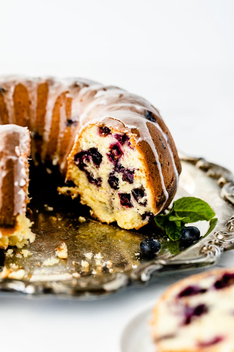 glazed blueberry pound cake on a silver platter cut open to see the inside of the cake