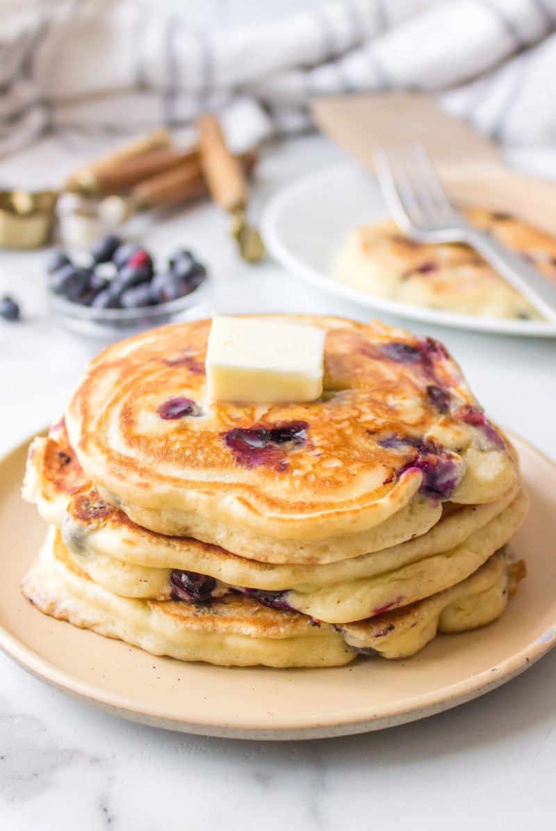 stack of blueberry pancakes with pat of butter on top