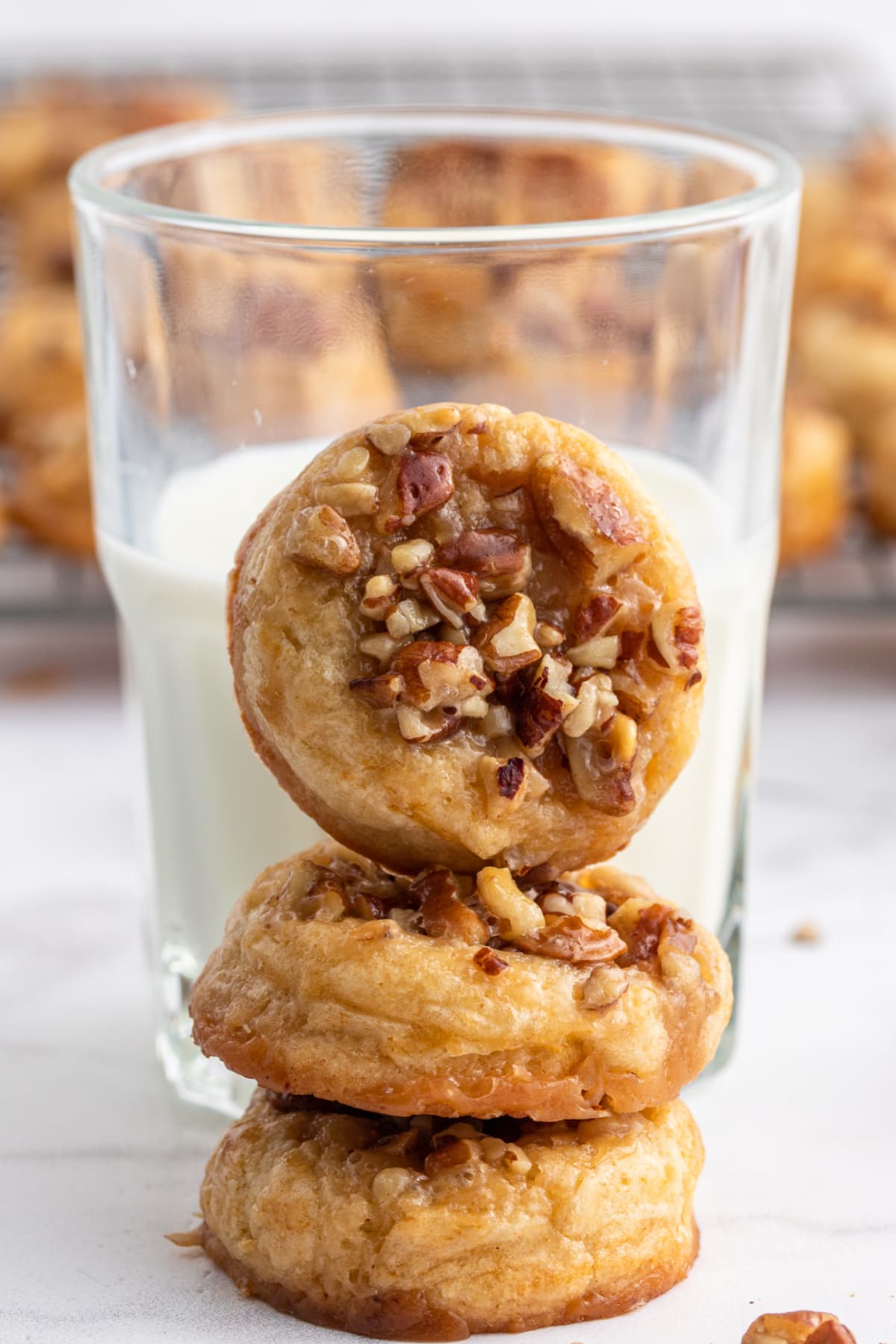 caramel pecan sticky bun cookies stacked with a glass of milk