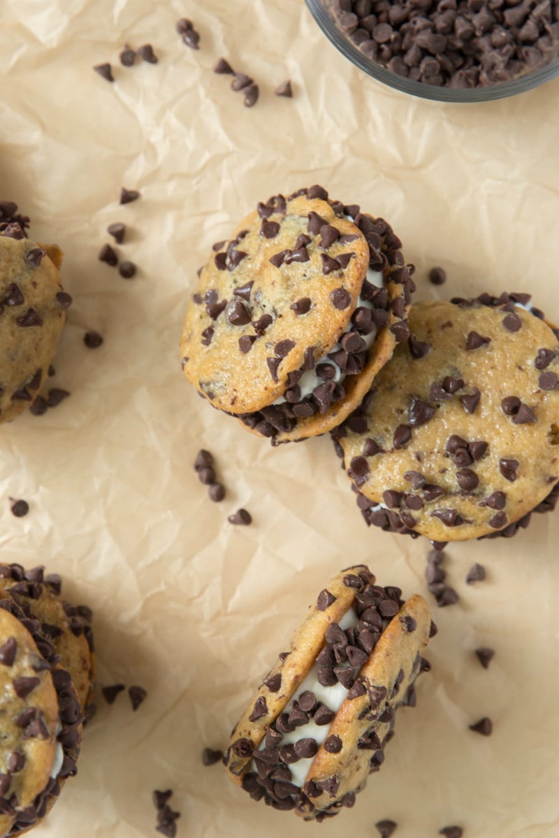 chocolate chip ice cream sandwiches on parchment paper with chocolate chips scattered around