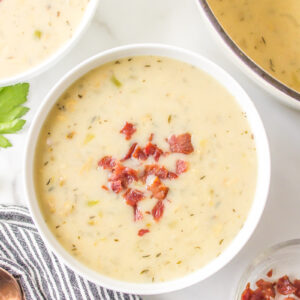 low fat clam chowder in a white bowl topped with bacon