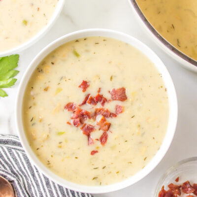 low fat clam chowder in a white bowl topped with bacon