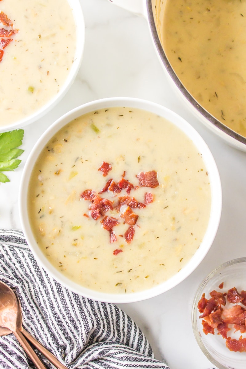 low fat clam chowder in a white bowl topped with bacon