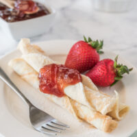 norwegian pancakes topped with strawberry jam with fresh strawberries