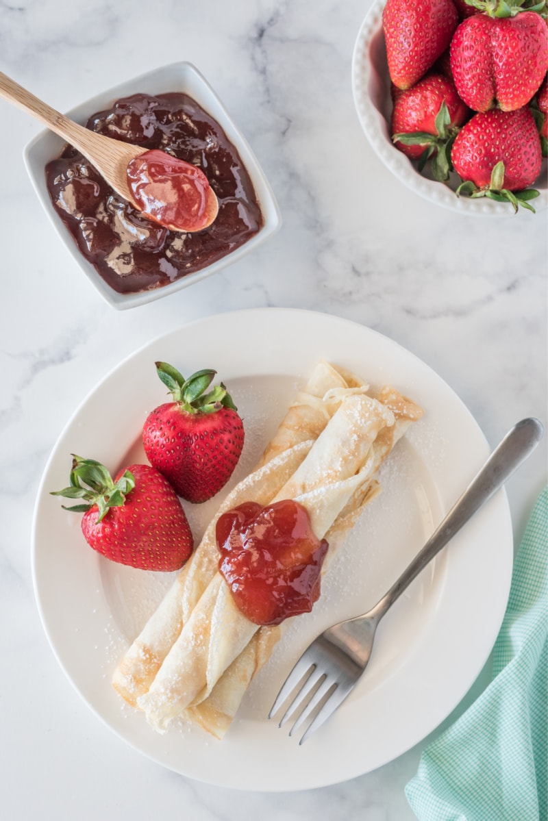 norwegian pancakes topped with strawberry jam with fresh strawberries