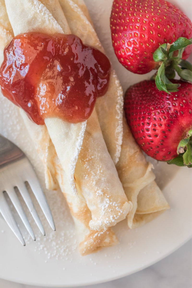 norwegian pancakes topped with strawberry jam with fresh strawberries