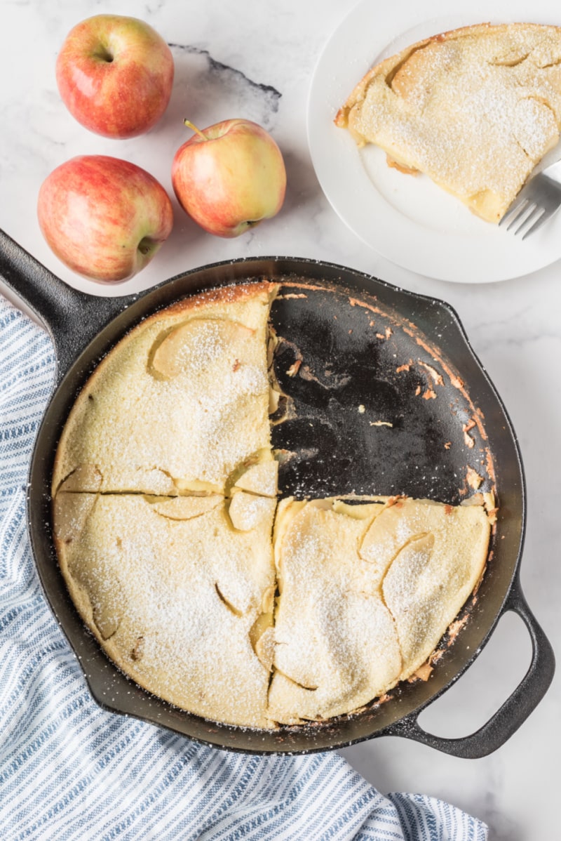 big apple pancake in cast iron skillet with piece cut out of it