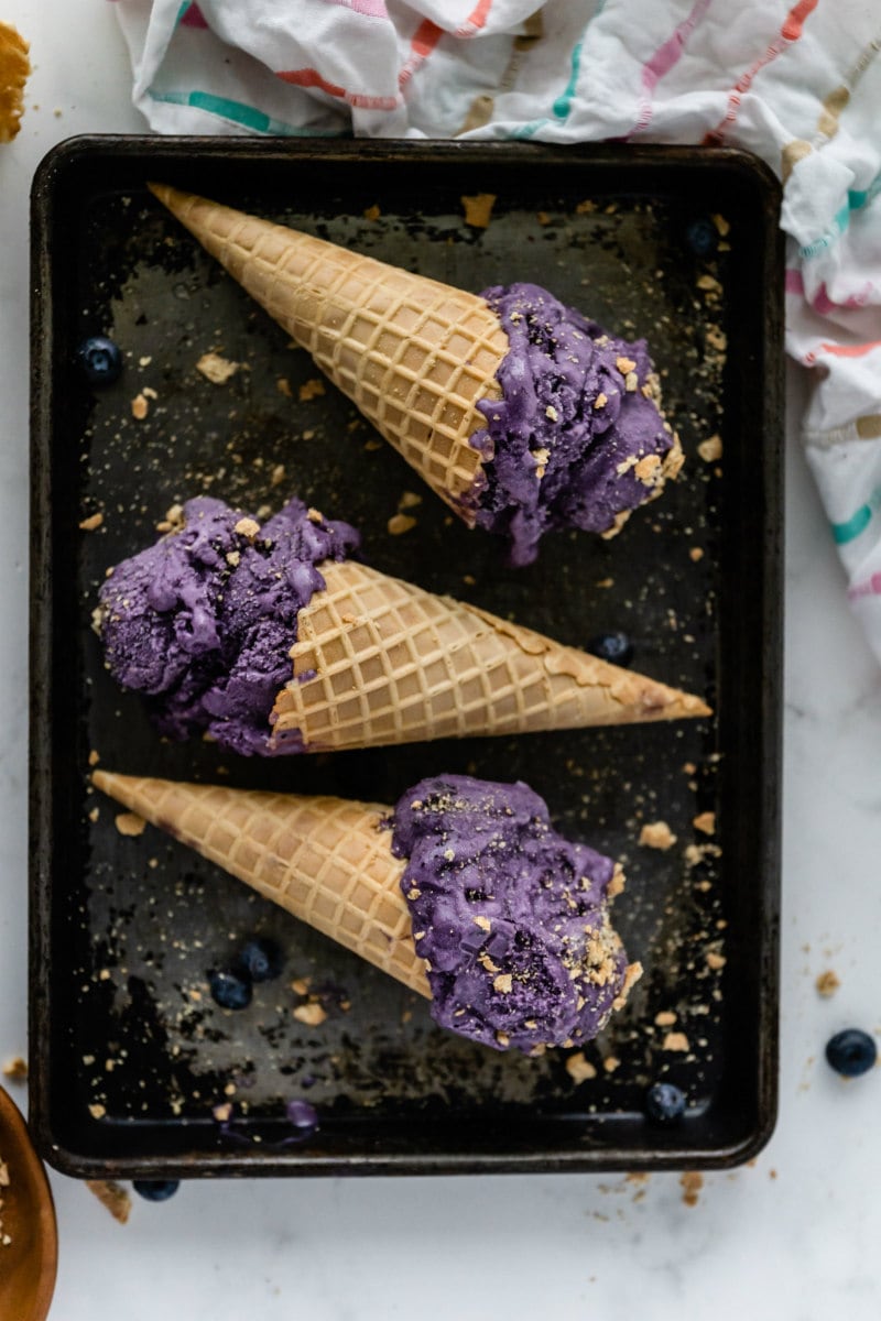 black tray with 3 blueberry cheesecake ice cream cones laying on top