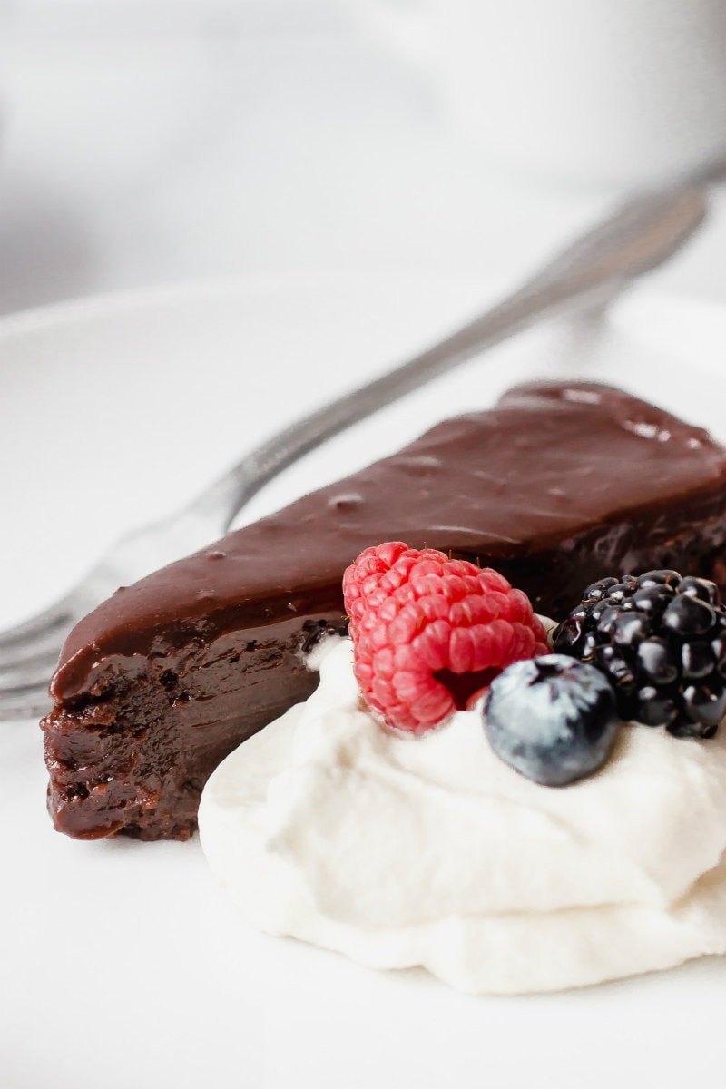 slice of chocolate truffle cake served with cream and berries