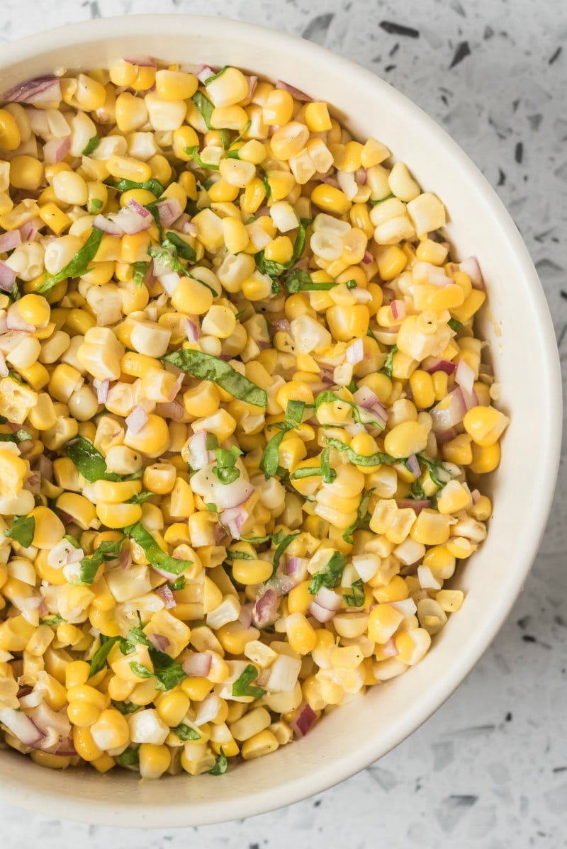 overhead shot of fresh corn salad in a white bowl