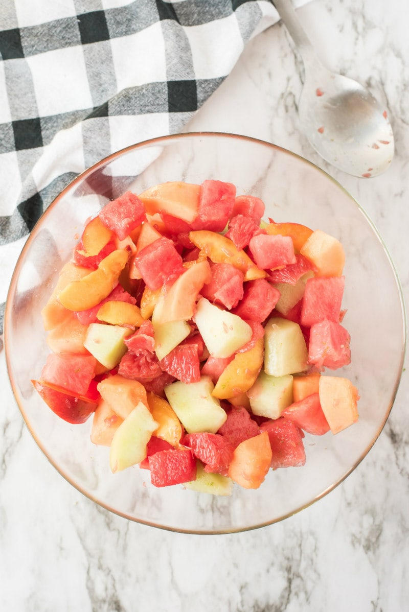 overhead shot of fruit salad in a glass bowl with black and white napkin in background