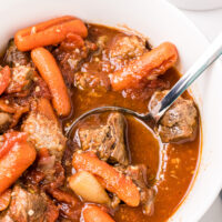 ladle of greek beef stew in a white bowl