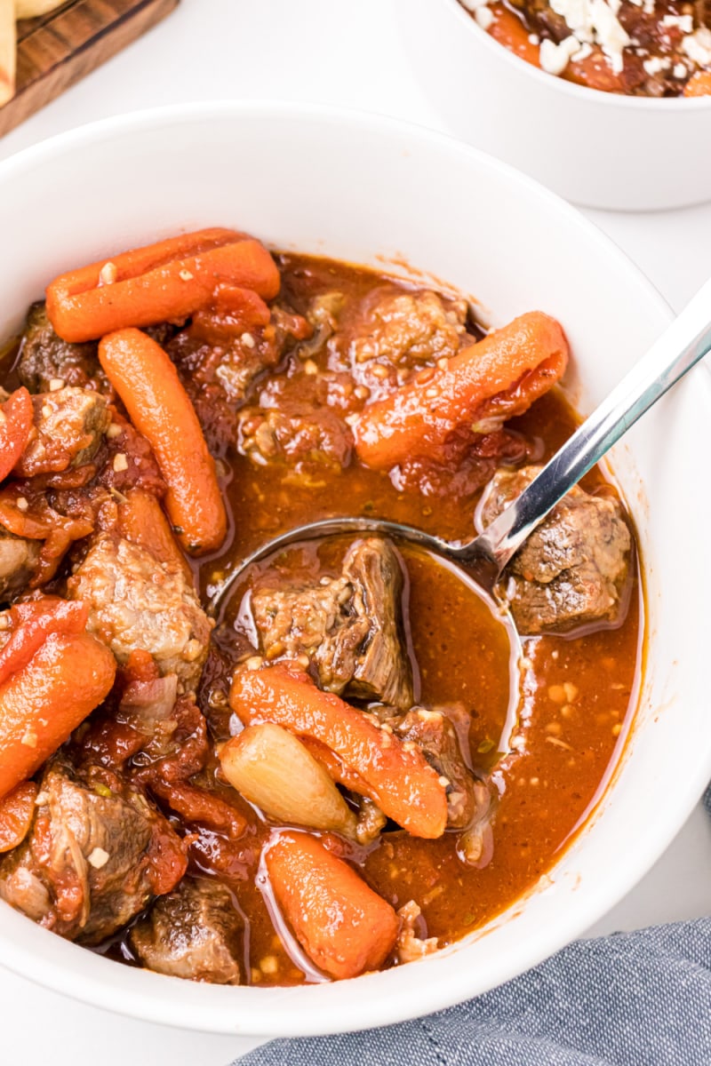 ladle of greek beef stew in a white bowl