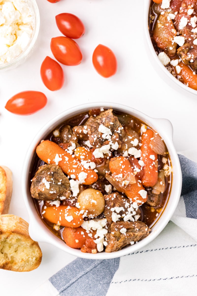 beef stew in a white bowl sprinkled with cheese