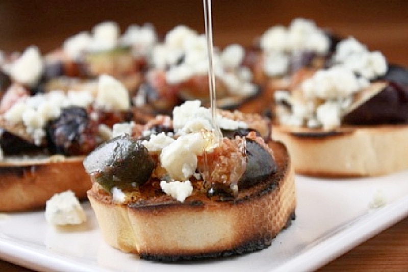 honey drizzling onto grilled fig bruschetta