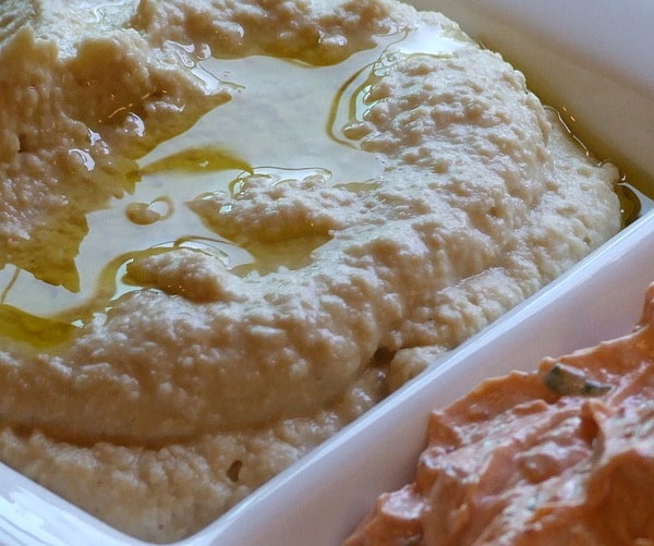 Hummus in a white bowl with a drizzle of olive oil on top