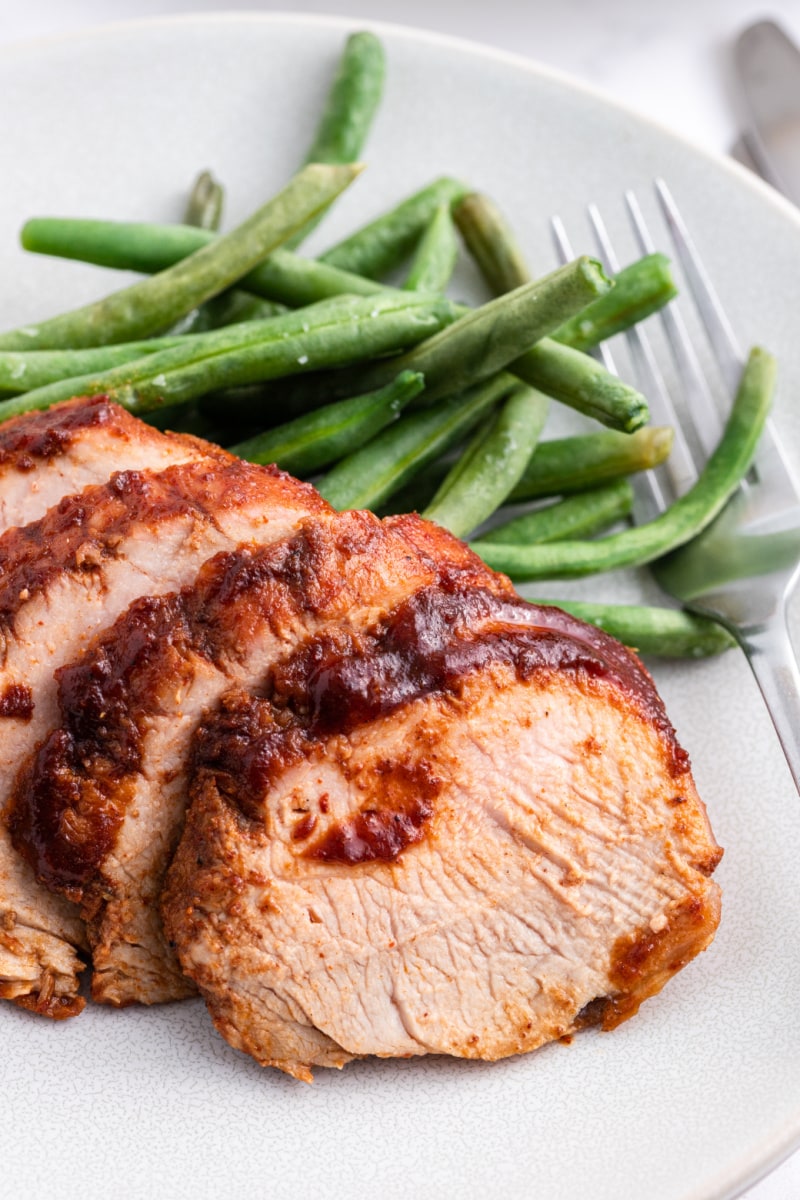 sweet and tangy roasted pork tenderloin on a plate with green beans