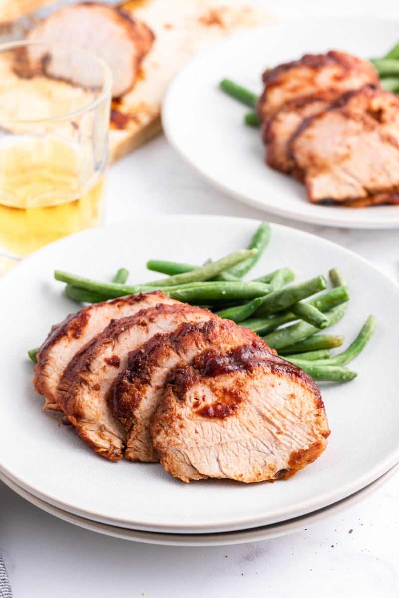 sliced pork on a plate with green beans