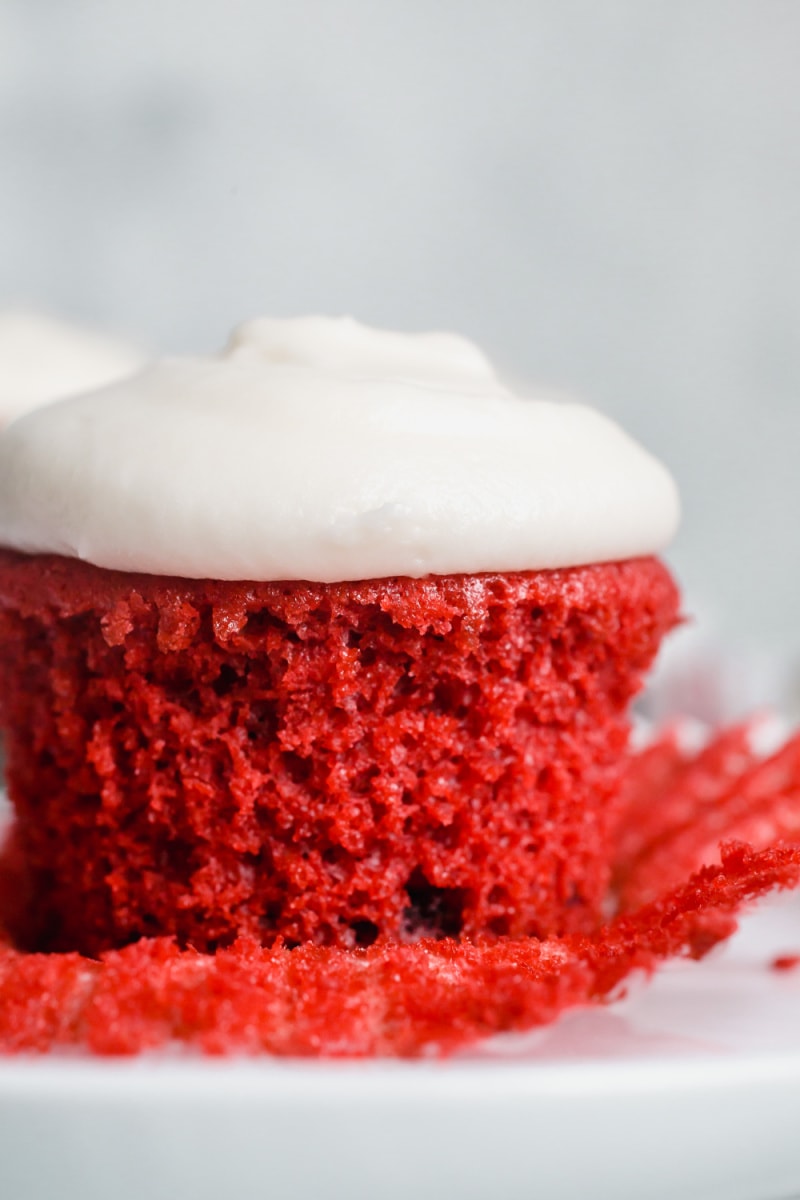 Red velvet cupcake with white frosting unwrapped