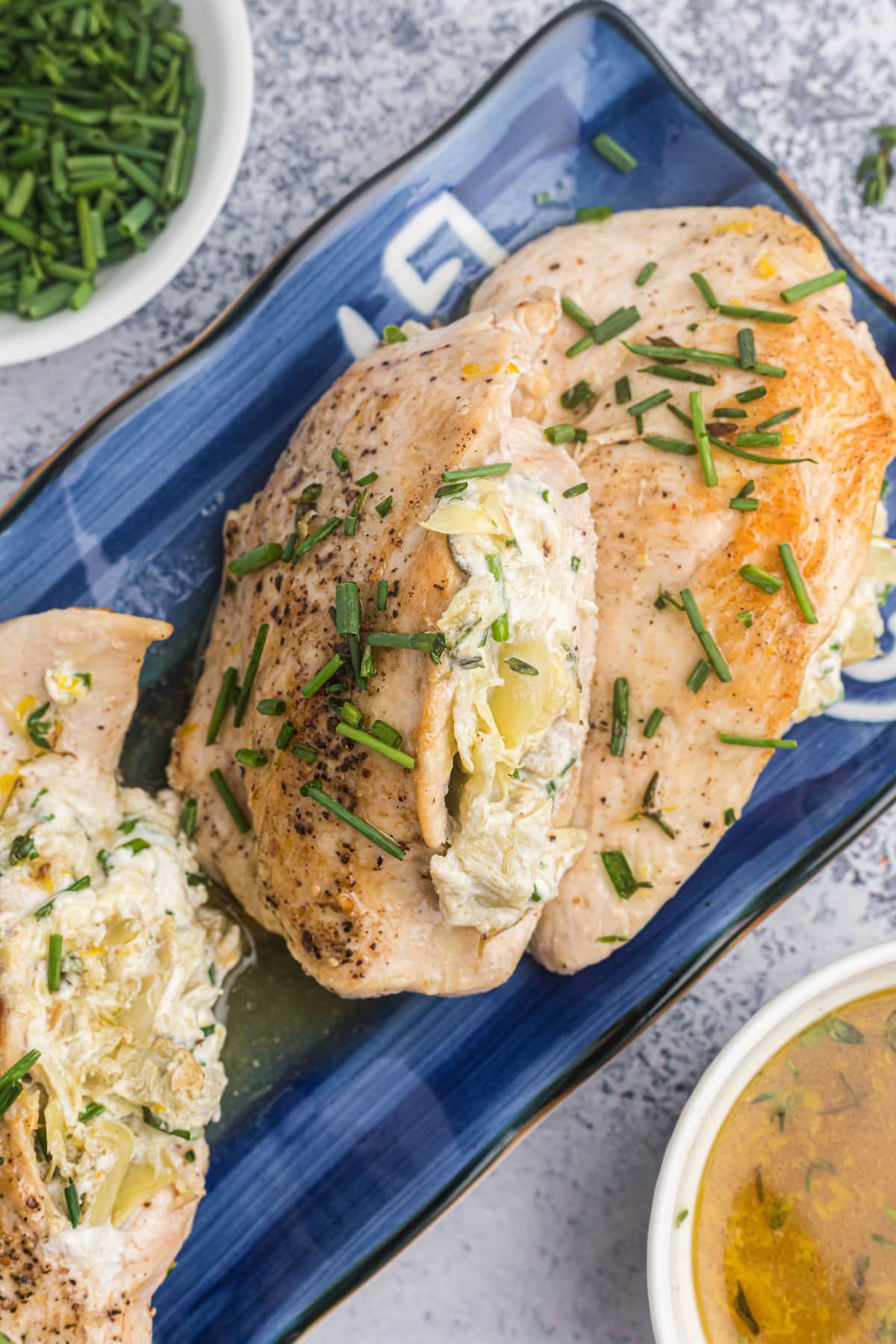 artichoke and goat cheese stuffed chicken on blue platter