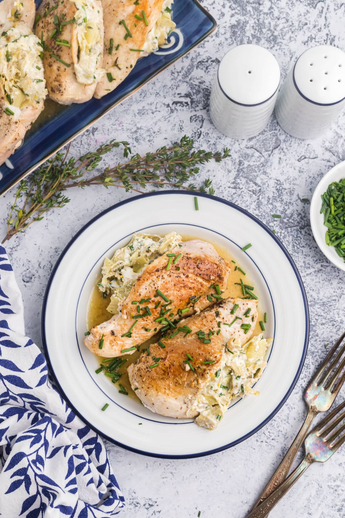 overhead shot of plate of two chicken breasts stuffed with artichoke and goat cheese