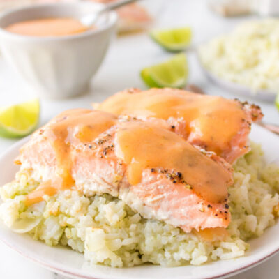 baked salmon on top of rice on a plate with coconut ginger sauce on top