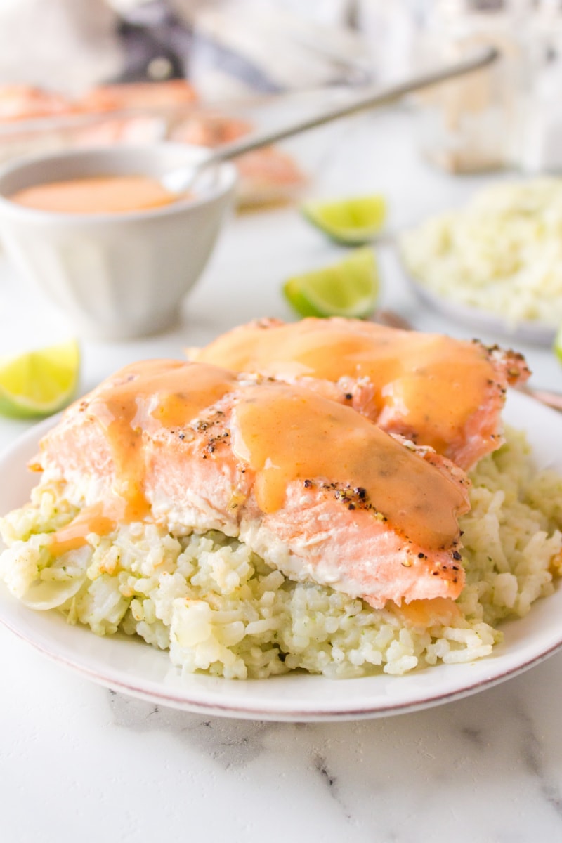 baked salmon on top of rice on a plate with coconut ginger sauce on top