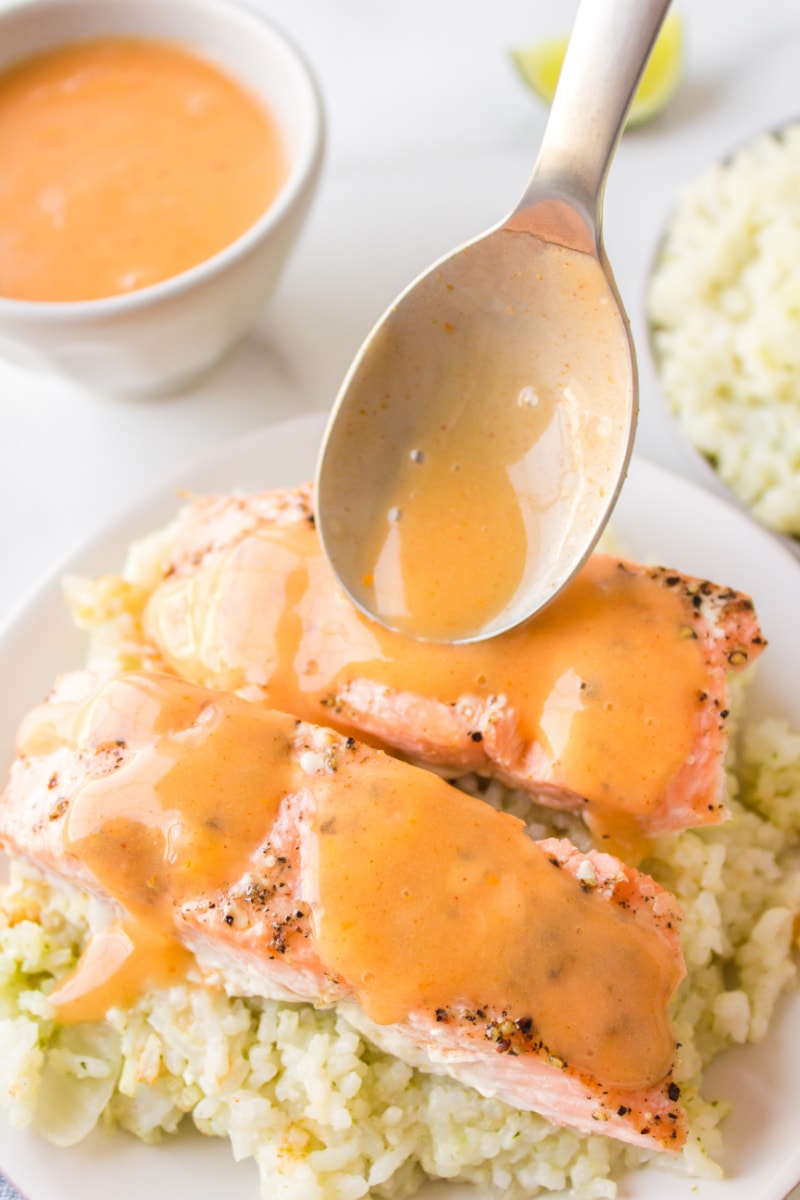 spooning coconut ginger sauce onto baked salmon