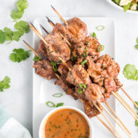 coconut curry pork satay skewers on platter with bowl of sauce