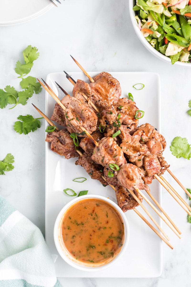 coconut curry pork satay skewers on platter with bowl of sauce