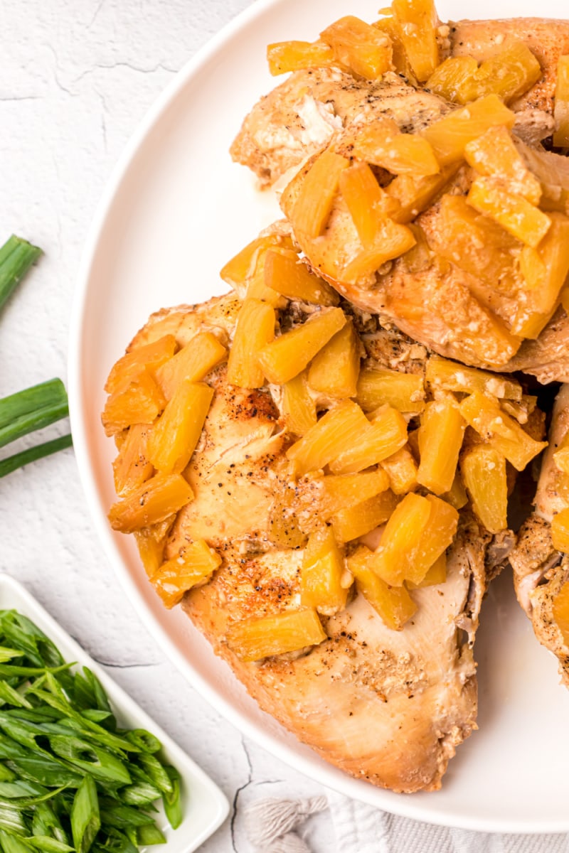 chicken breasts on plate topped with pineapple tidbits