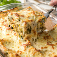 using spatula to lift out a piece of lasagna out of the pan